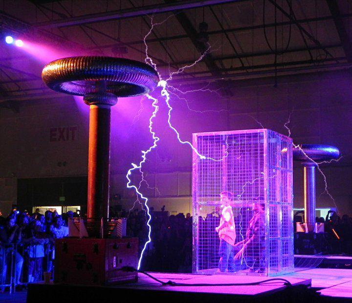 A performer inside a Faraday cage with controlled lightning arcs during ELECTRIFIED!